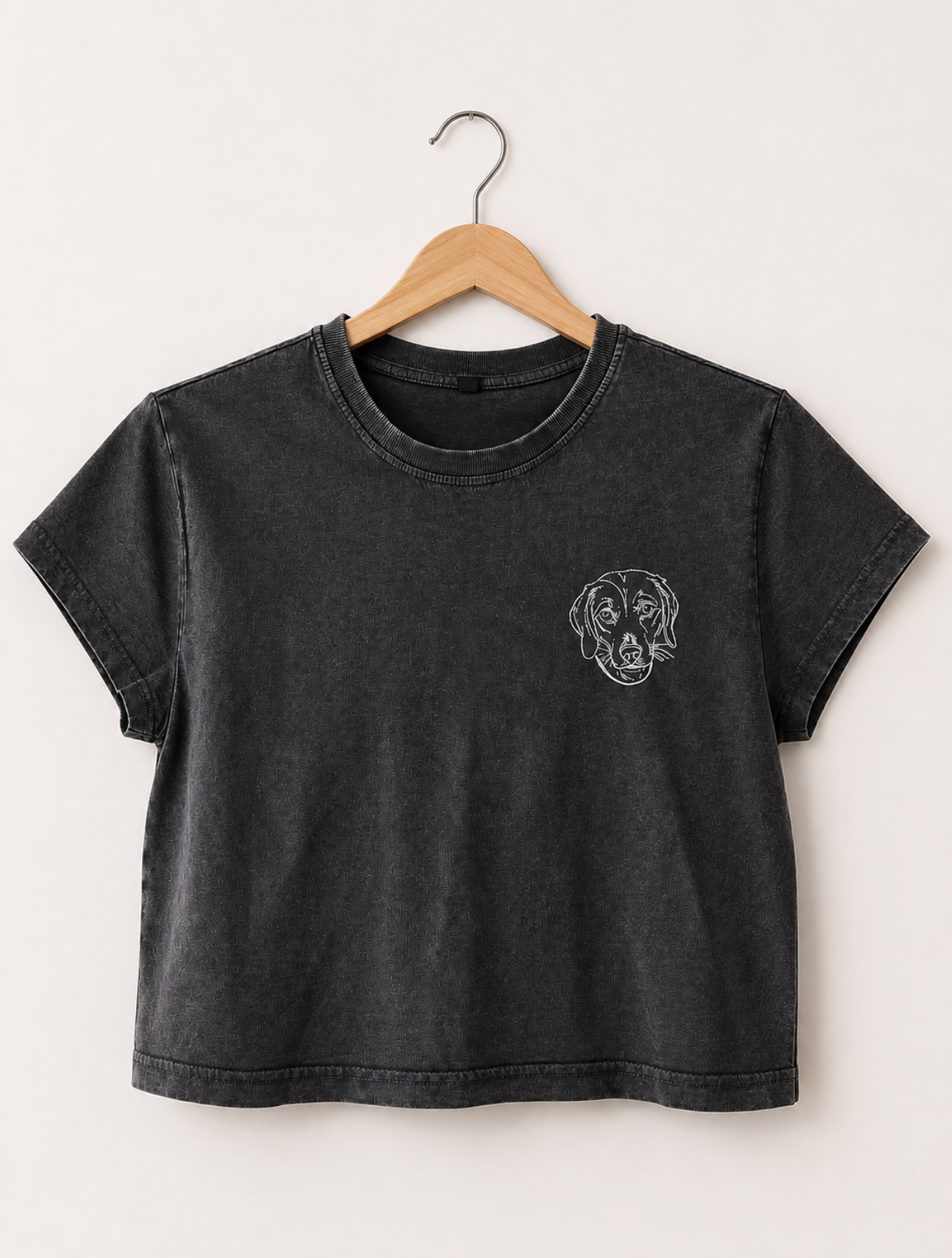 Black t-shirt with a logo on a wooden hanger against a white background